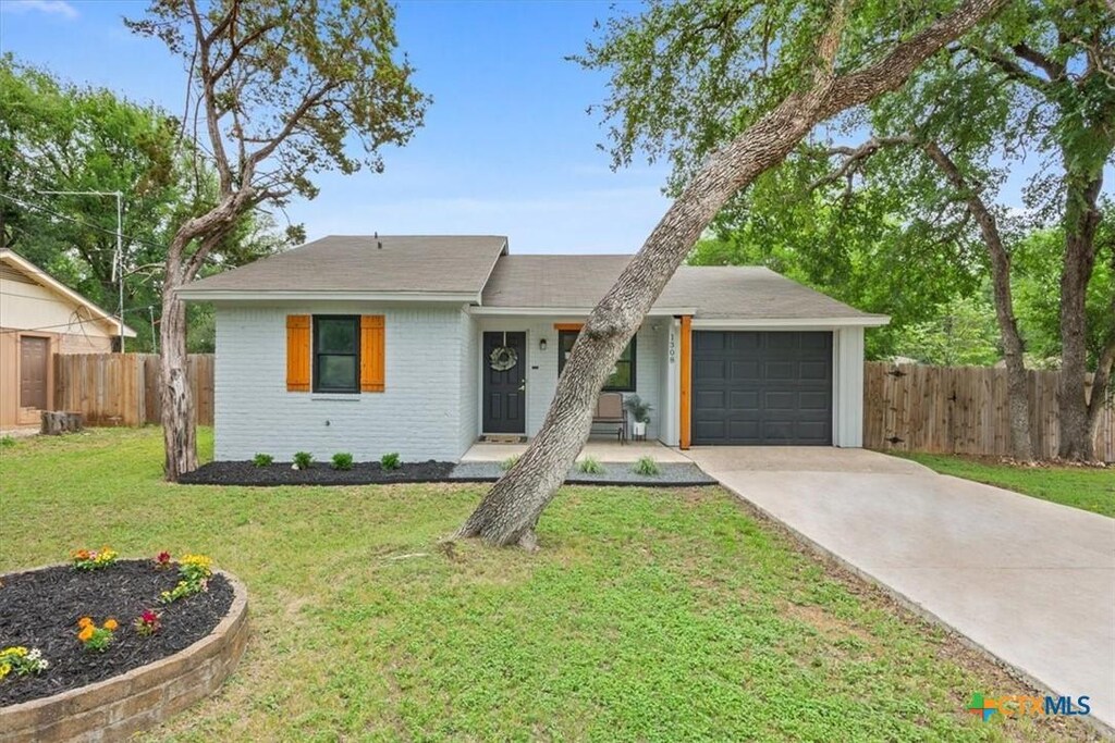view of front of property with a garage, a front lawn, fence, brick siding, and concrete driveway