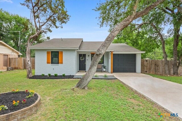 view of front of property with a garage, a front lawn, fence, brick siding, and concrete driveway