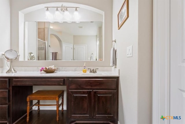 bathroom featuring an enclosed shower, vanity, and wood-type flooring