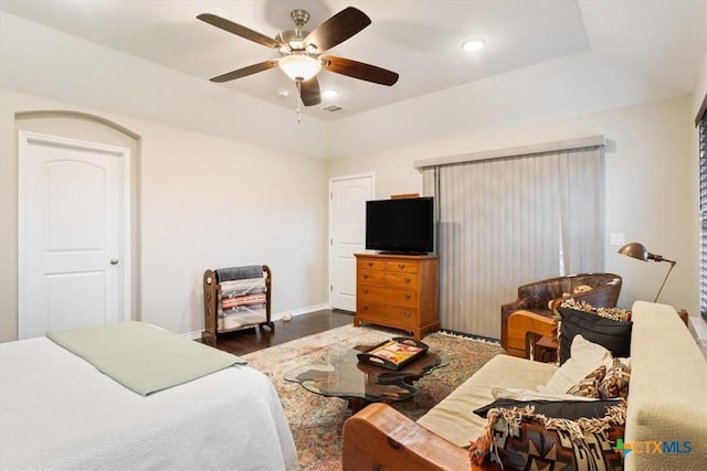 bedroom featuring ceiling fan, a tray ceiling, and dark hardwood / wood-style floors