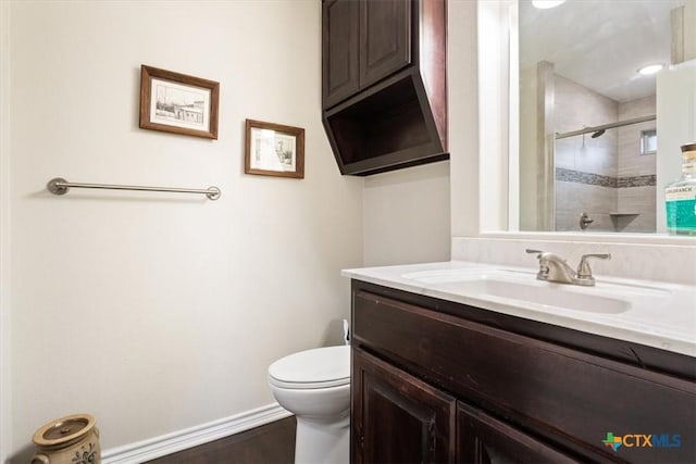 bathroom with toilet, hardwood / wood-style flooring, walk in shower, and vanity