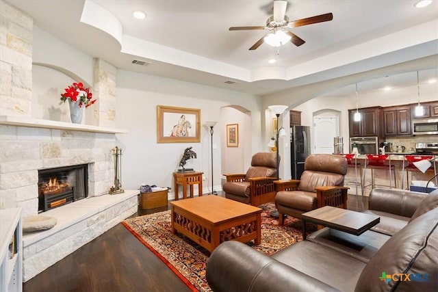 living room with ceiling fan, hardwood / wood-style floors, a fireplace, and a tray ceiling