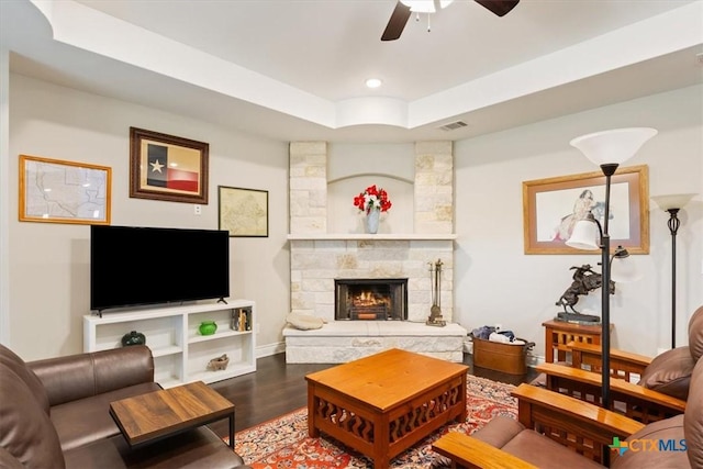 living room with a fireplace, ceiling fan, a tray ceiling, and hardwood / wood-style flooring