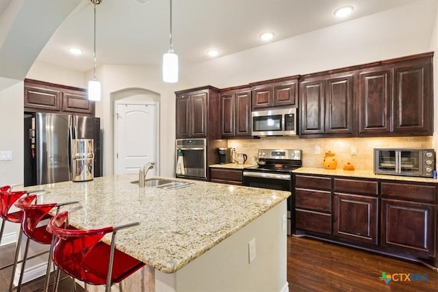 kitchen featuring hanging light fixtures, an island with sink, tasteful backsplash, appliances with stainless steel finishes, and sink