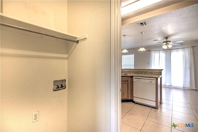 clothes washing area with a textured ceiling, hookup for a washing machine, ceiling fan, and light tile patterned floors