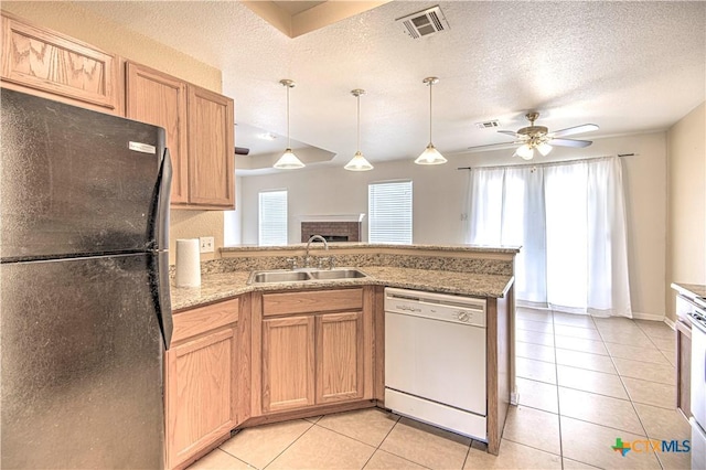 kitchen featuring white dishwasher, light tile patterned floors, sink, black fridge, and kitchen peninsula