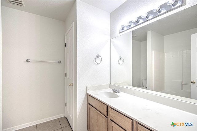 bathroom with vanity, walk in shower, a textured ceiling, tile patterned flooring, and toilet