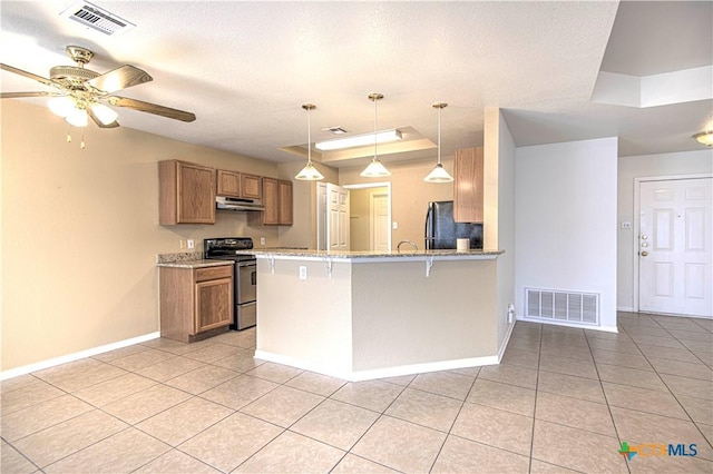 kitchen featuring kitchen peninsula, stainless steel appliances, a breakfast bar, a tray ceiling, and pendant lighting