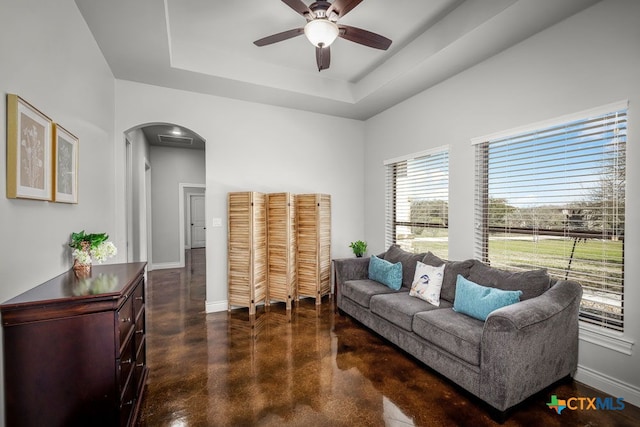 750 Cambridge Dr, New Braunfels, TX 78132 - living room with finished concrete floors, arched walkways, ceiling fan, a tray ceiling, and baseboards