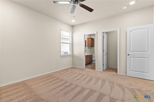 unfurnished bedroom featuring light carpet, ceiling fan, and ensuite bath