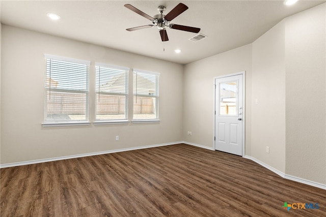 spare room with ceiling fan, a wealth of natural light, and dark hardwood / wood-style floors