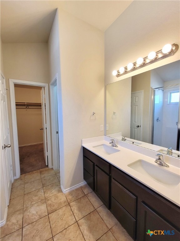 full bath with double vanity, a spacious closet, a sink, and tile patterned floors