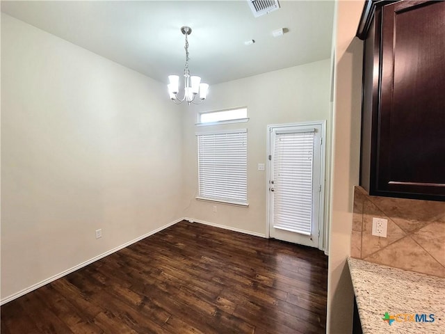 unfurnished dining area featuring a chandelier, dark wood-type flooring, visible vents, and baseboards