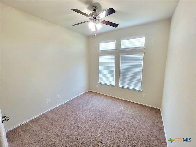 carpeted spare room with a ceiling fan and baseboards