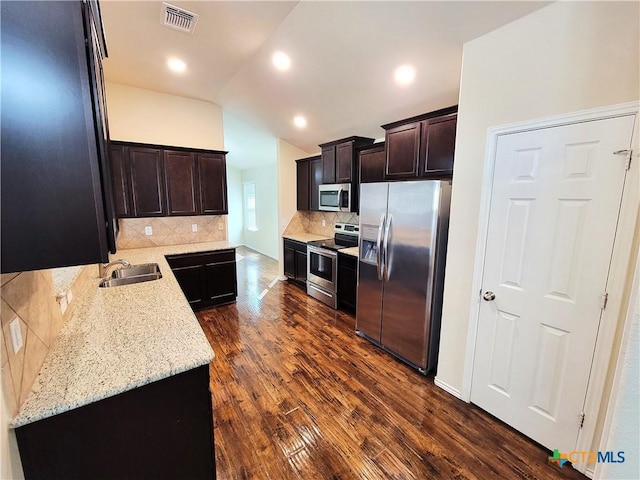 kitchen featuring lofted ceiling, a sink, visible vents, appliances with stainless steel finishes, and dark wood finished floors