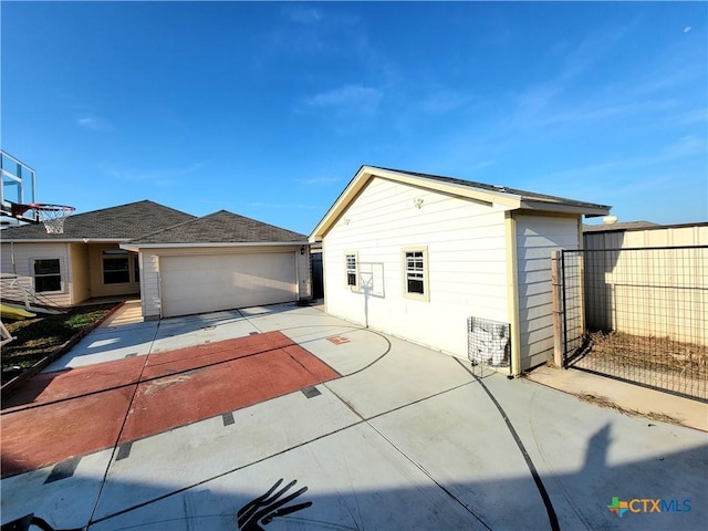 view of home's exterior featuring a garage, concrete driveway, and fence