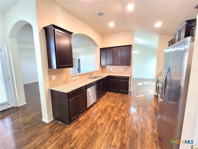 kitchen with dark brown cabinetry, visible vents, appliances with stainless steel finishes, dark wood-style flooring, and backsplash