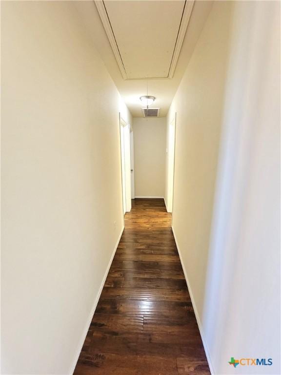 hallway with baseboards, attic access, visible vents, and dark wood-type flooring