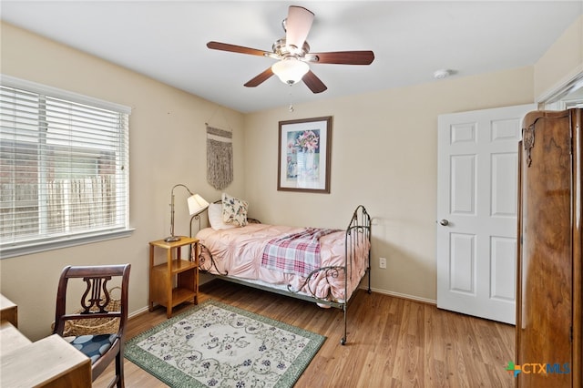 bedroom featuring baseboards, light wood-style floors, and a ceiling fan