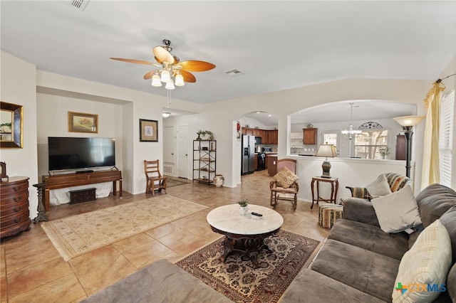 living area featuring visible vents, light tile patterned floors, ceiling fan with notable chandelier, and arched walkways