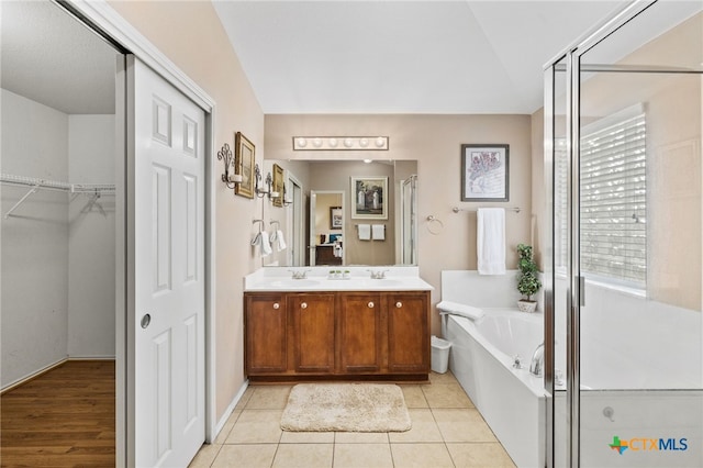 bathroom with double vanity, a stall shower, a sink, tile patterned floors, and a bath