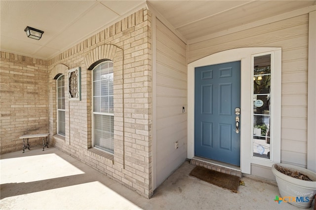 entrance to property featuring brick siding and a porch