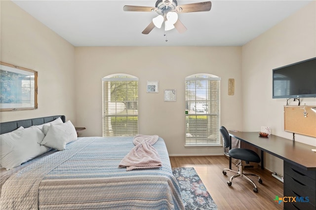 bedroom with multiple windows, wood finished floors, and a ceiling fan