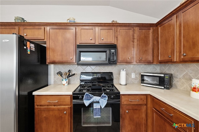 kitchen featuring lofted ceiling, black appliances, and brown cabinets