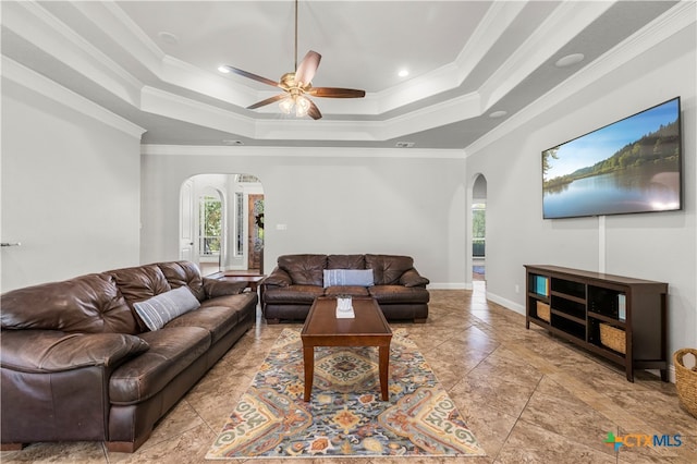 living room featuring ornamental molding, ceiling fan, and a tray ceiling