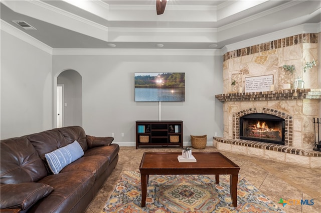 living room featuring a fireplace, a raised ceiling, and ornamental molding