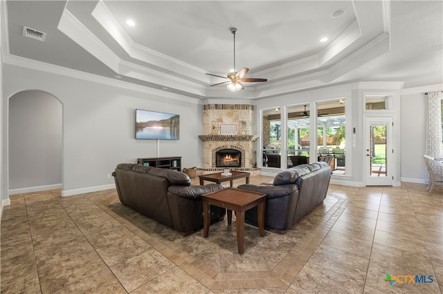 living room featuring a fireplace, ceiling fan, crown molding, and a tray ceiling