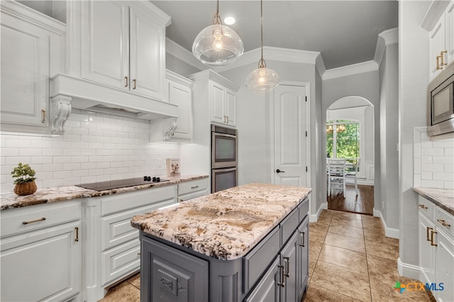 kitchen featuring ornamental molding, stainless steel appliances, white cabinetry, gray cabinets, and a center island