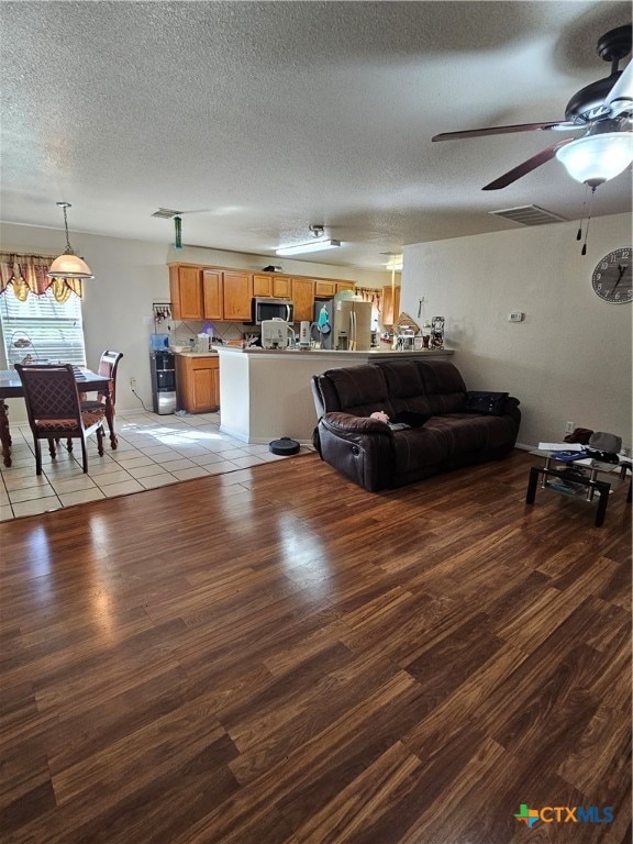 living room with a textured ceiling, light hardwood / wood-style floors, and ceiling fan