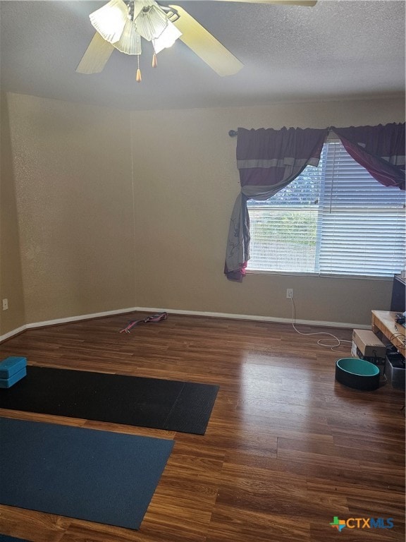 unfurnished room featuring a textured ceiling, ceiling fan, and dark wood-type flooring