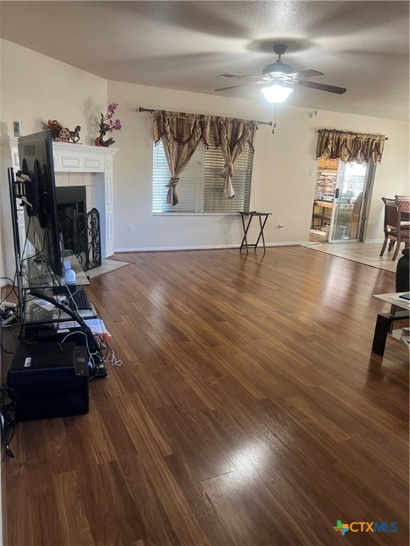 unfurnished living room with ceiling fan, dark wood-type flooring, and a textured ceiling