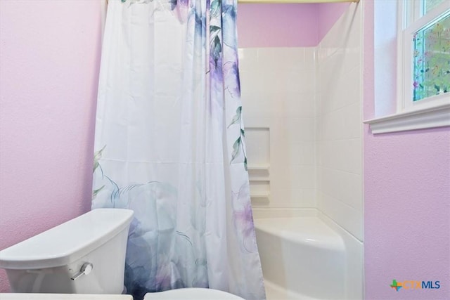 bathroom featuring shower / bath combo, a textured wall, and toilet