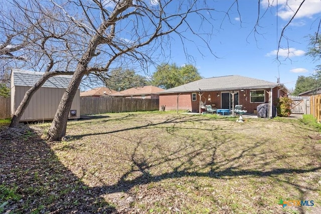 rear view of house featuring an outbuilding, a fenced backyard, brick siding, a lawn, and a shed