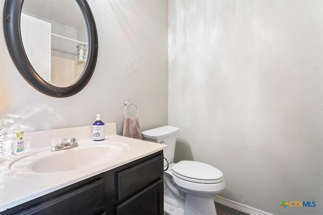 bathroom featuring toilet, baseboards, and vanity