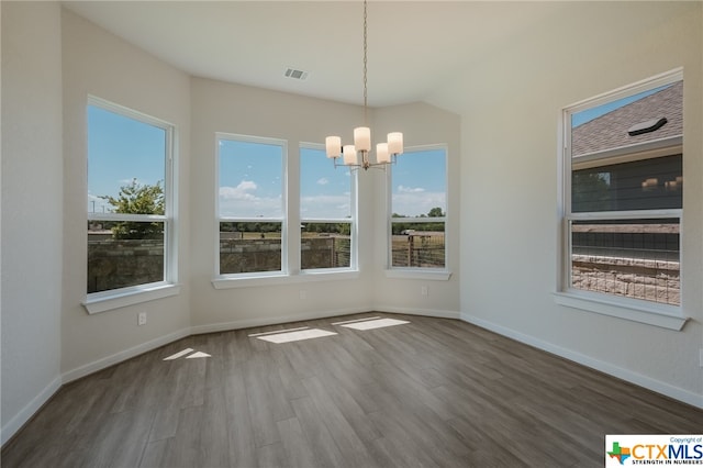 unfurnished dining area featuring dark wood-type flooring and an inviting chandelier