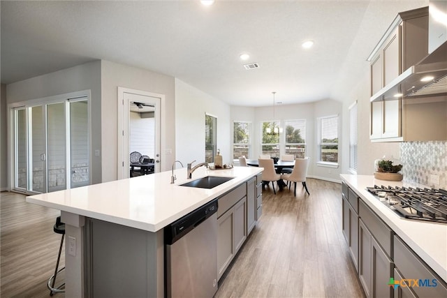 11305 Hollering Pass, Schertz, TX 78154 - kitchen featuring appliances with stainless steel finishes, wall chimney exhaust hood, gray cabinetry, light wood-style flooring, and recessed lighting
