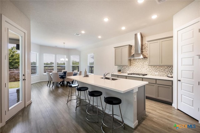 11305 Hollering Pass, Schertz, TX 78154 - kitchen with wall chimney range hood, gray cabinets, a breakfast bar, dark wood-style flooring, and recessed lighting