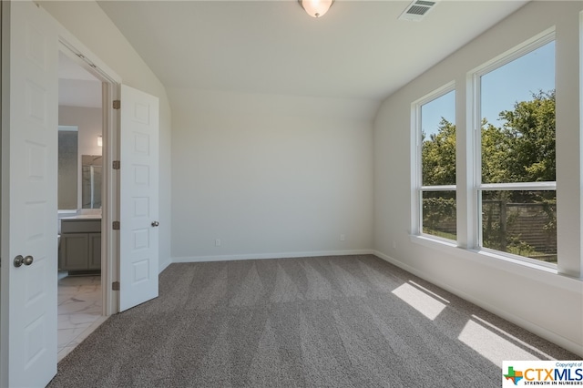 carpeted spare room featuring vaulted ceiling