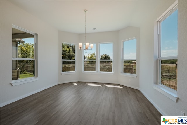 unfurnished dining area featuring dark hardwood / wood-style flooring and an inviting chandelier