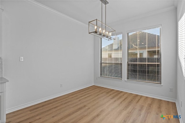 unfurnished dining area featuring a notable chandelier, light wood-style floors, baseboards, and crown molding