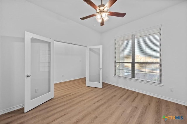 unfurnished bedroom with french doors, a ceiling fan, vaulted ceiling, wood finished floors, and baseboards