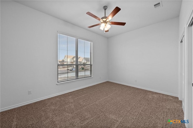 unfurnished room with carpet floors, baseboards, visible vents, and a ceiling fan