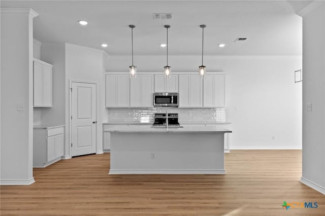 kitchen with stainless steel appliances, white cabinets, light countertops, light wood-type flooring, and decorative backsplash