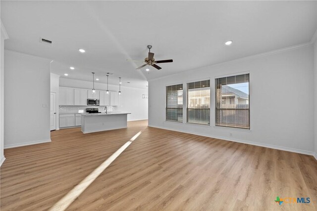 unfurnished living room with ceiling fan, ornamental molding, light wood finished floors, and visible vents