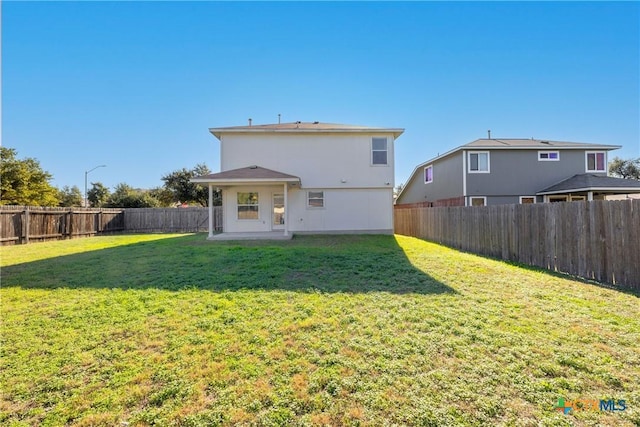 rear view of property featuring a lawn and a patio area