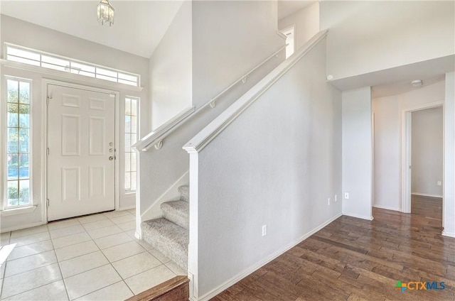 foyer entrance featuring a towering ceiling, a healthy amount of sunlight, and light wood-type flooring